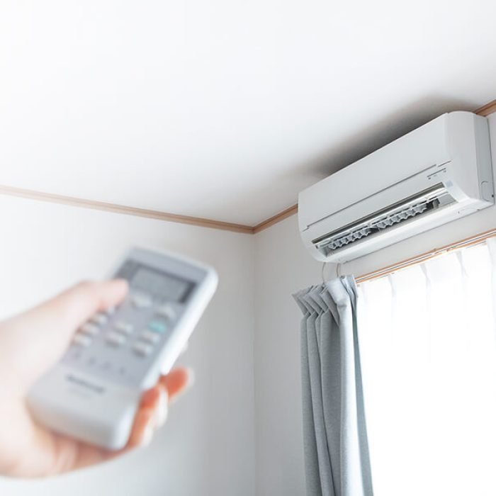 a person holding a remote control turning on an air conditioner